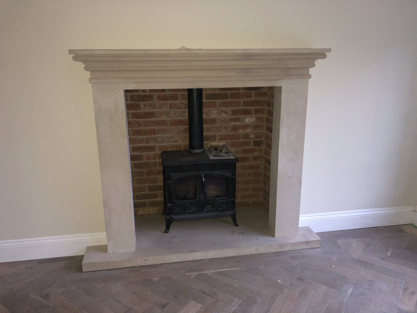 A stone fireplace surround with a brick fireback and wood-burning stove